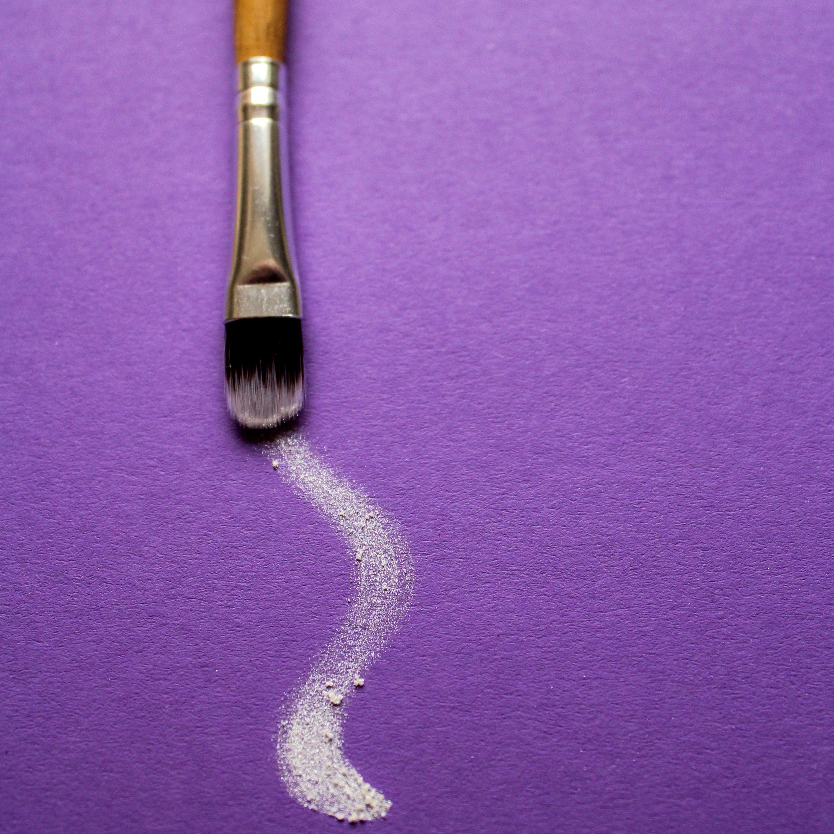 a-paintbrush-trails-white-paint-on-purple-paper.jpg