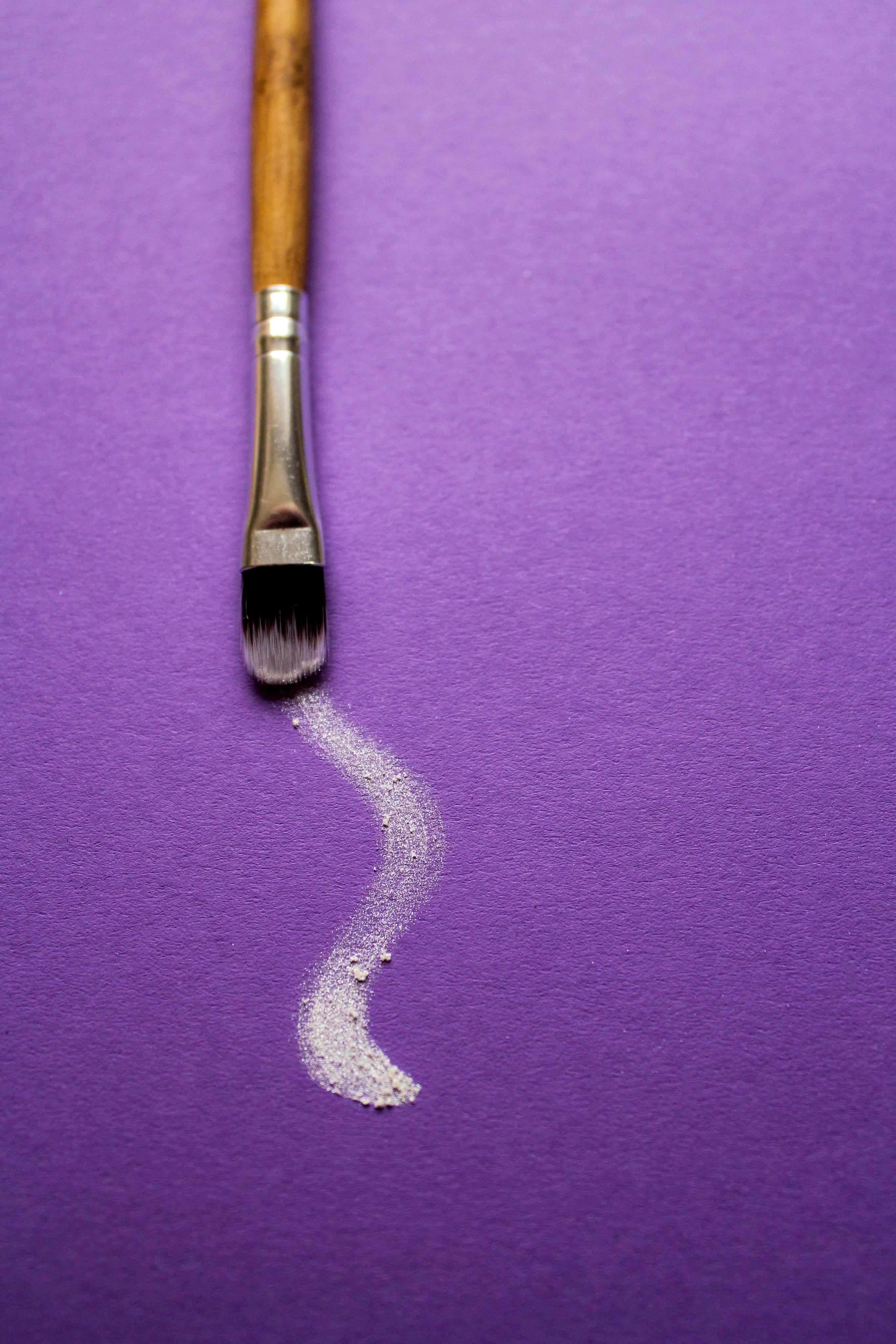 a-paintbrush-trails-white-paint-on-purple-paper.jpg